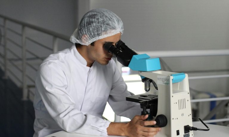 A man in the R&D market looking into a microscope, sterilization services by industry,