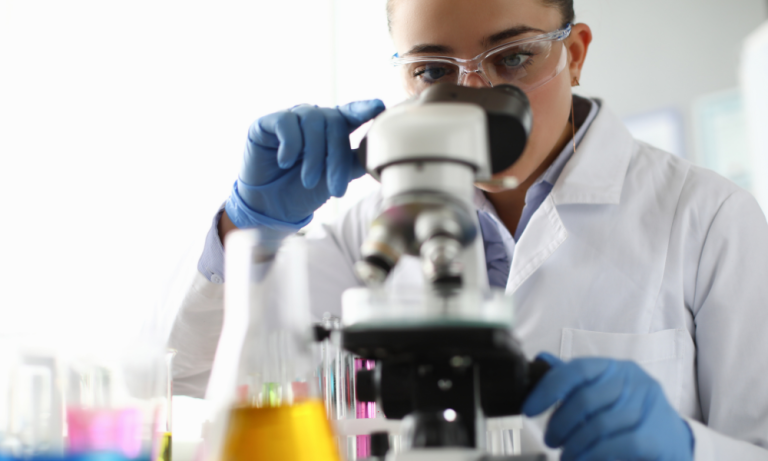 Scientist looking in microscope at a sterilization company.